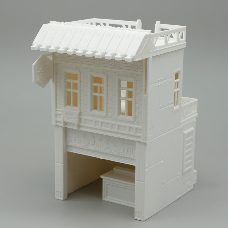 Weißes Modell eines zweistöckigen japanischen Hauses mit offenem Erdgeschoss und filigranen Fensterdetails.