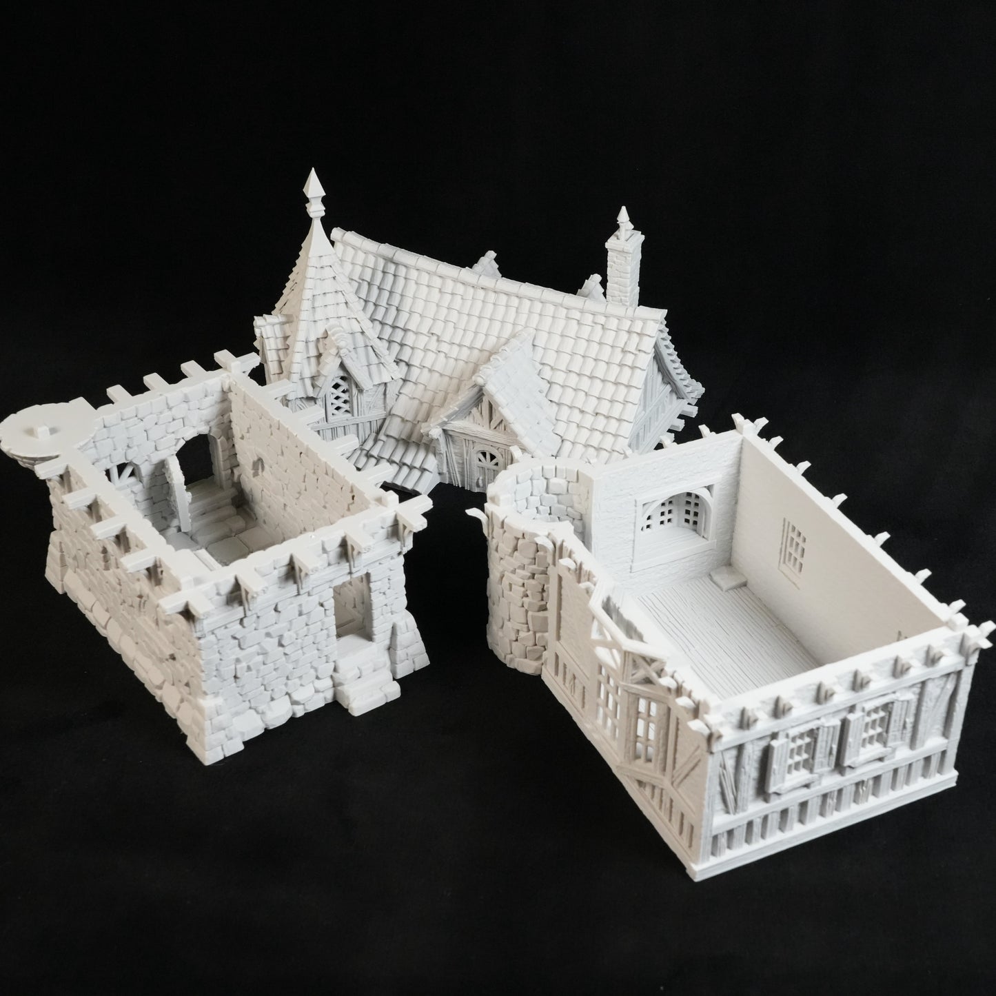 Drei weiße 3D-gedruckte Miniaturgebäude von Nebelstein Prints - ein gotisches Haus, das Herrenhaus des Gouverneurs und ein detailliertes mittelalterliches Bauwerk - werden auf schwarzem Grund präsentiert und eignen sich perfekt als Tabletop-Gelände.