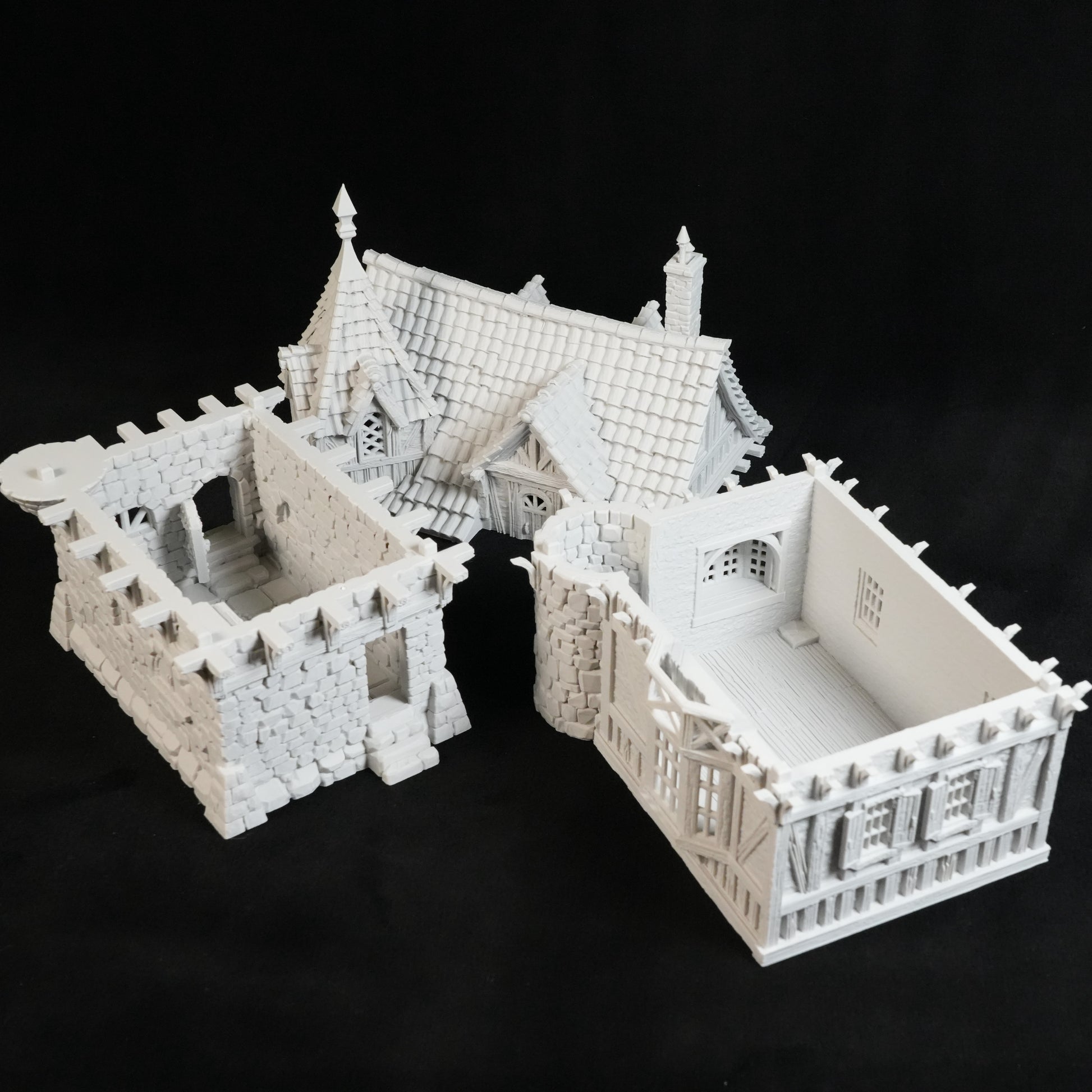 Drei weiße 3D-gedruckte Miniaturgebäude von Nebelstein Prints - ein gotisches Haus, das Herrenhaus des Gouverneurs und ein detailliertes mittelalterliches Bauwerk - werden auf schwarzem Grund präsentiert und eignen sich perfekt als Tabletop-Gelände.