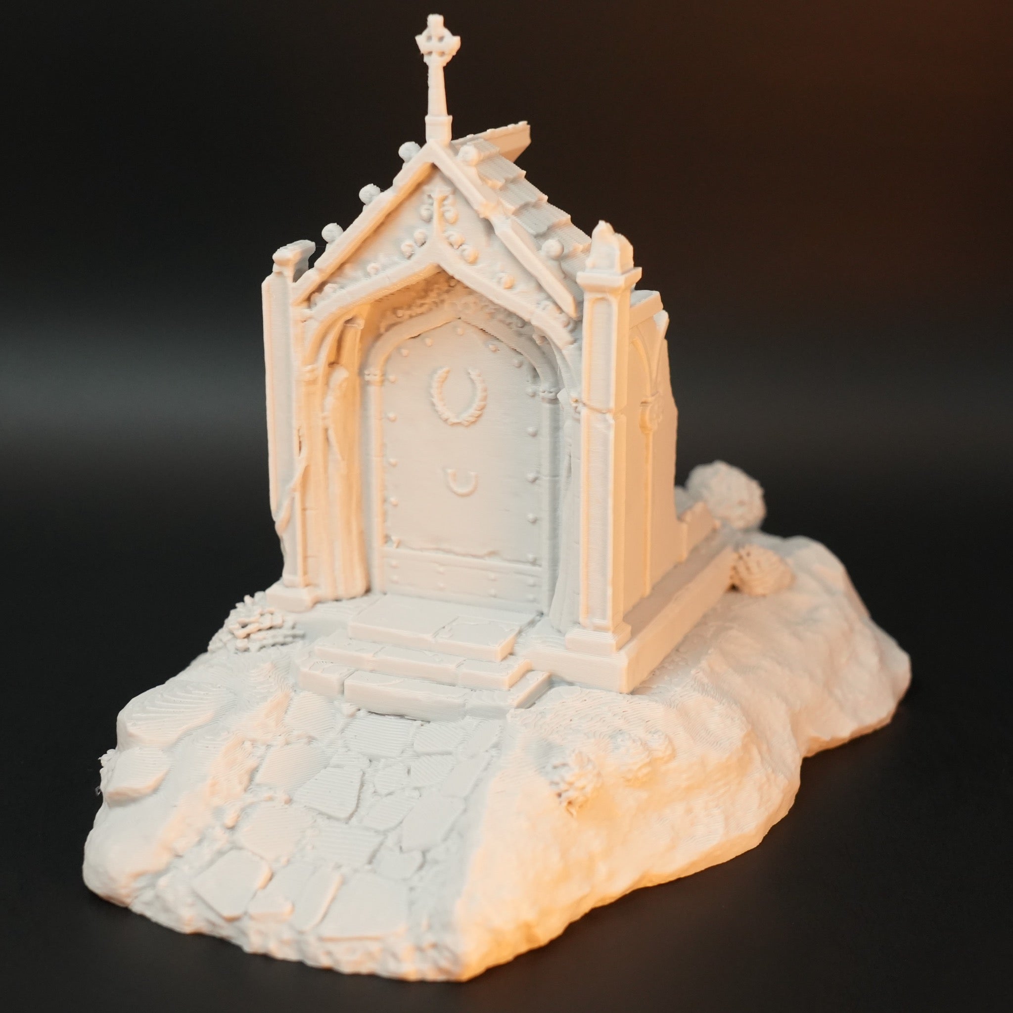 Helle, detaillierte Gruft-Kulisse mit Türen, Giebel und einem Weg aus Steinplatten auf unebenem Gelände.