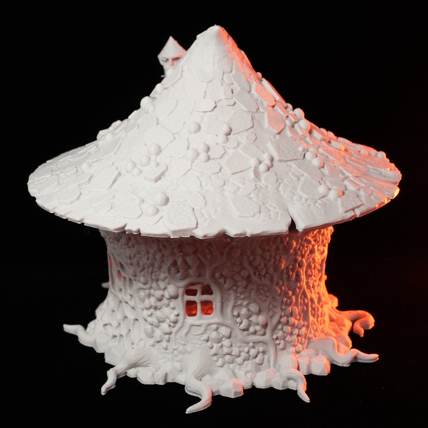 Weißes Modell einer Pilzhütte mit strukturierter, spitz zulaufender Kuppel und kleinem Fenster, fantasievoll gestaltet.