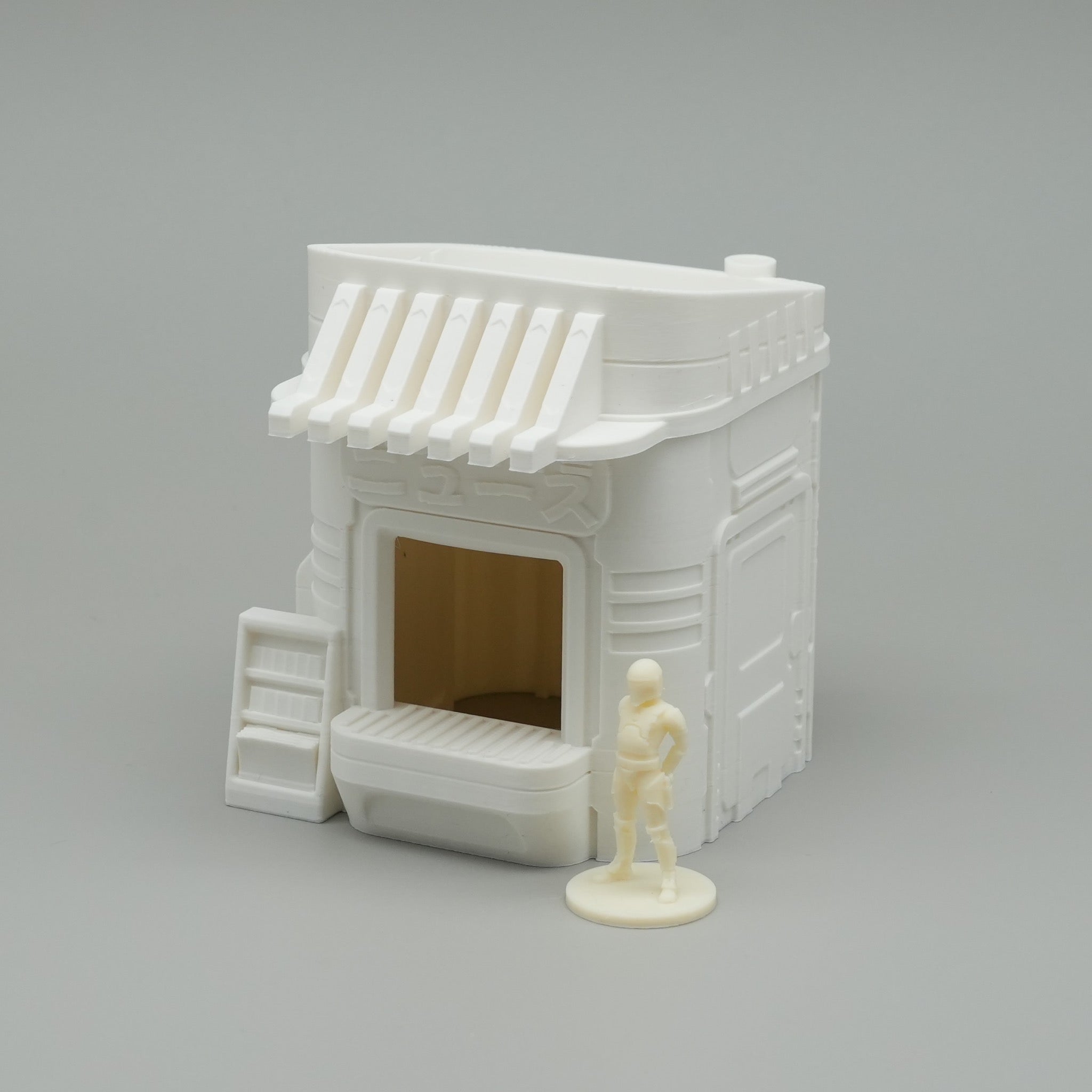 Miniatur-weißer japanischer Zeitungsstand mit markantem Vordach und offener Front, kleine Figur daneben.