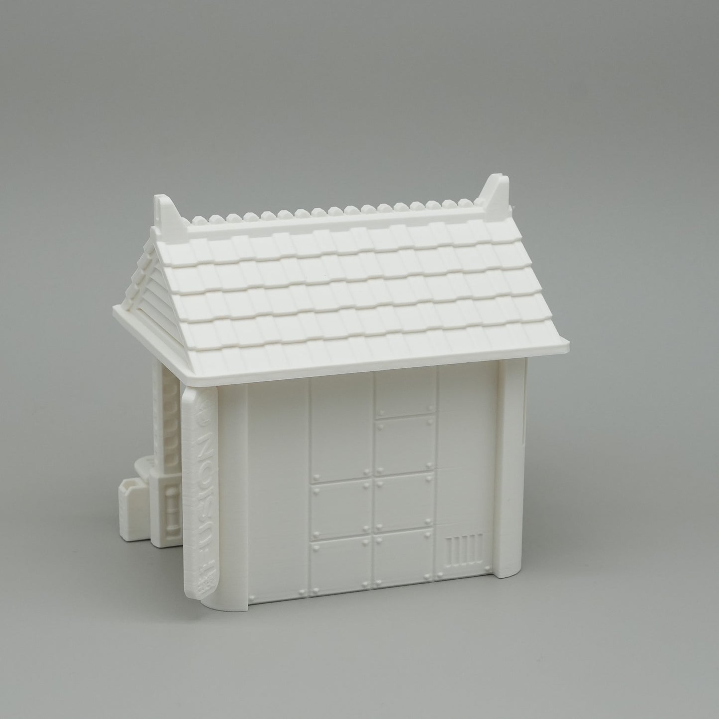 Weißes Miniaturhaus mit traditionellem japanischem Dach und geschlossener Tür.