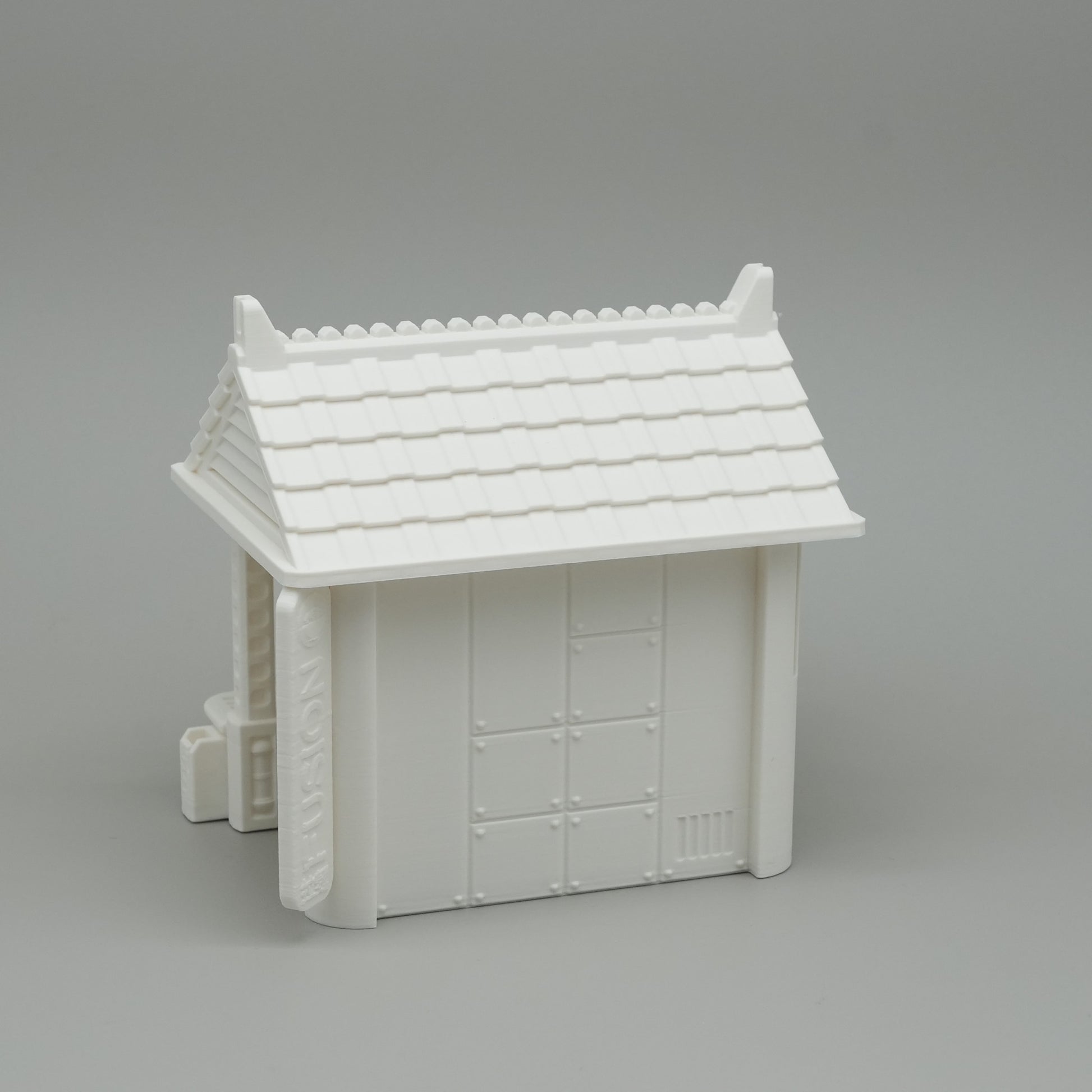 Weißes Miniaturhaus mit traditionellem japanischem Dach und geschlossener Tür.