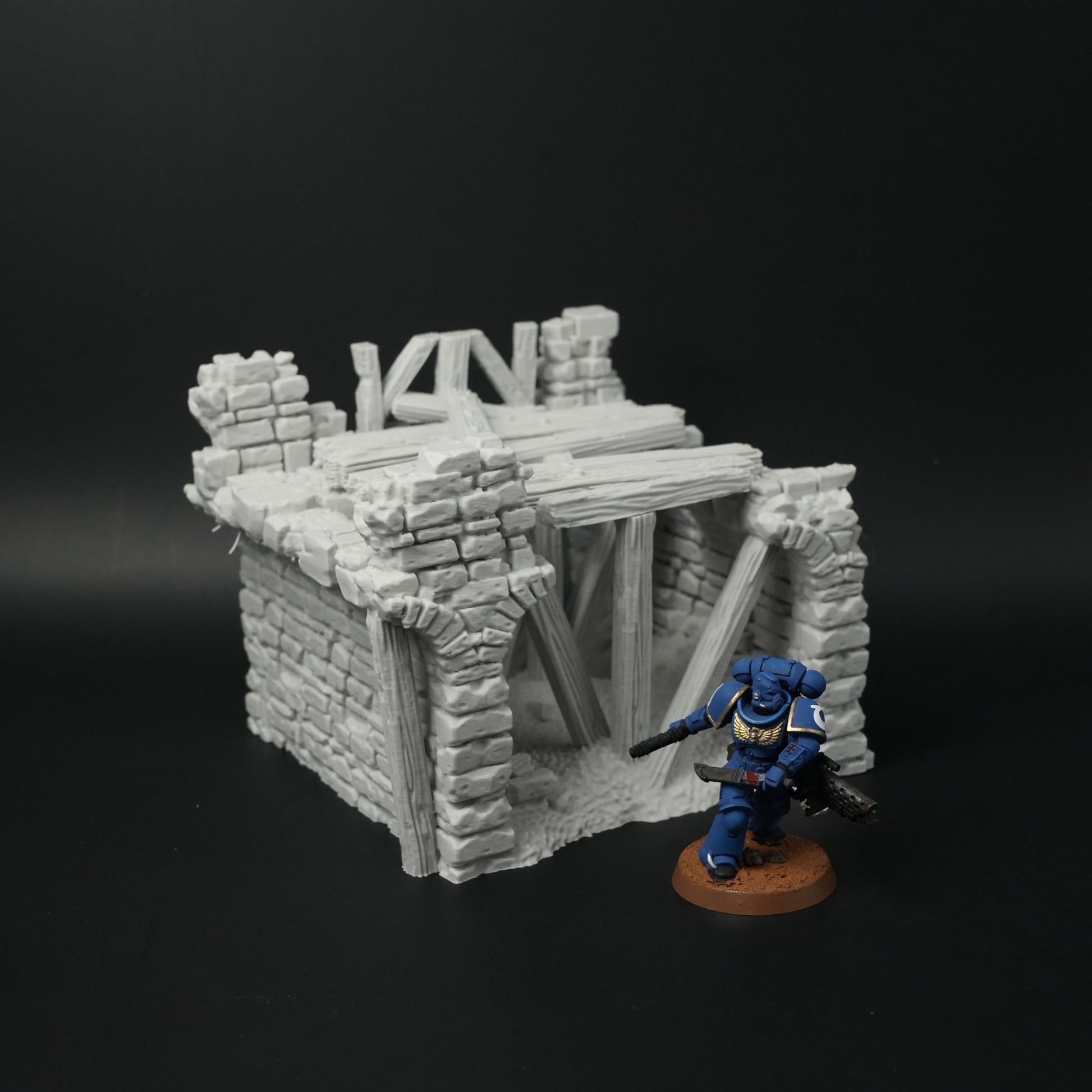 Zerfallene Steinbrücke mit Holzbalken auf schwarzem Hintergrund, daneben Miniaturfigur.