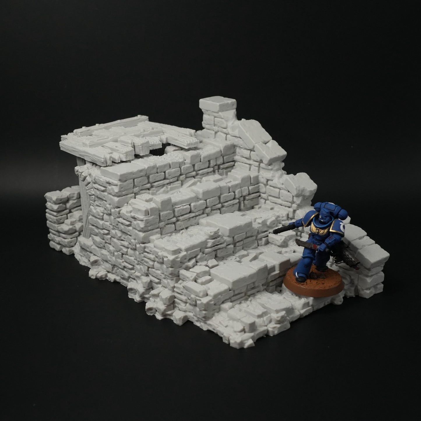 Graue, zerfallene Brückenruine aus Stein mit Treppen und unregelmäßigen Mauerstücken, Miniaturfigur daneben.