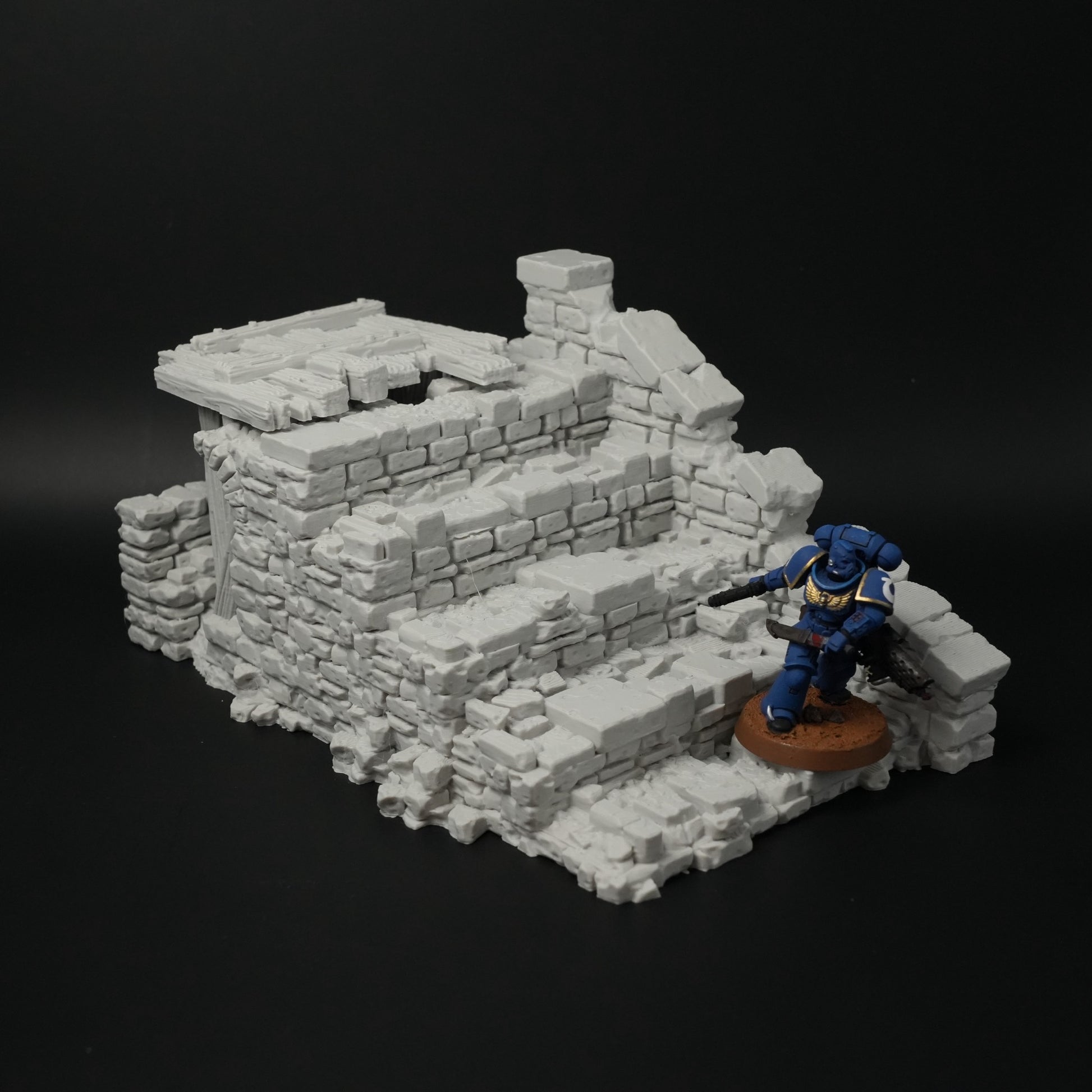 Graue, zerfallene Brückenruine aus Stein mit Treppen und unregelmäßigen Mauerstücken, Miniaturfigur daneben.