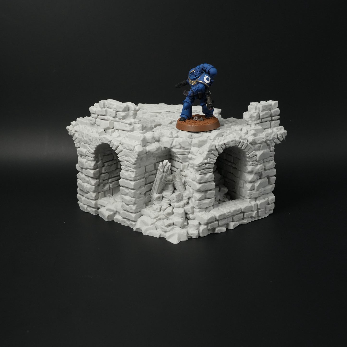 Zerfallene graue Steinbrücke mit drei Torbögen und zertrümmerten Mauerteilen, Miniaturmaßstab.