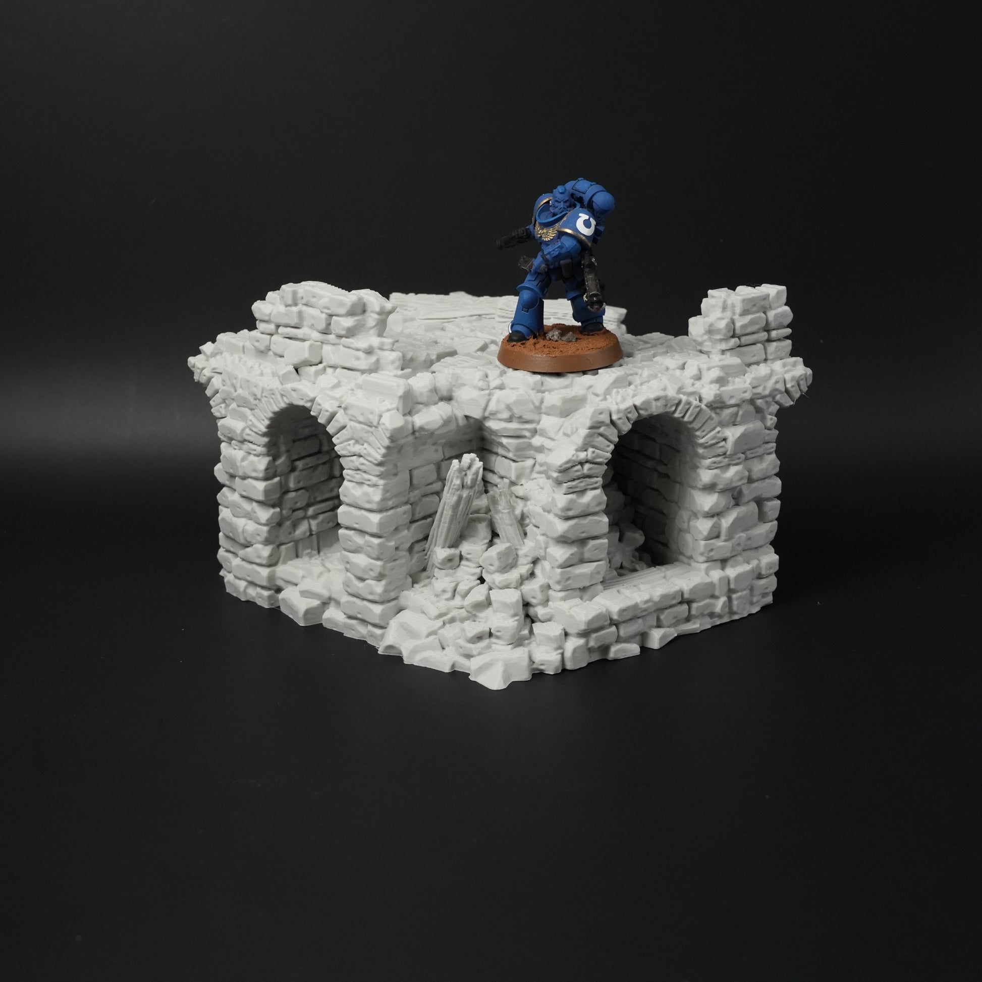 Zerfallene graue Steinbrücke mit drei Torbögen und zertrümmerten Mauerteilen, Miniaturmaßstab.