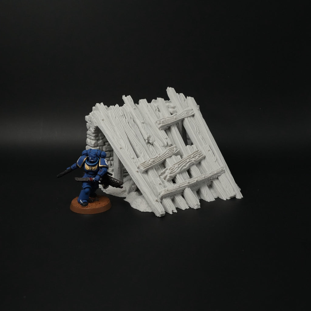 Weißes, zerfallenes Holzbrückengeländer aus dicken, schräg gestapelten Balken mit sichtbaren Beschädigungen.