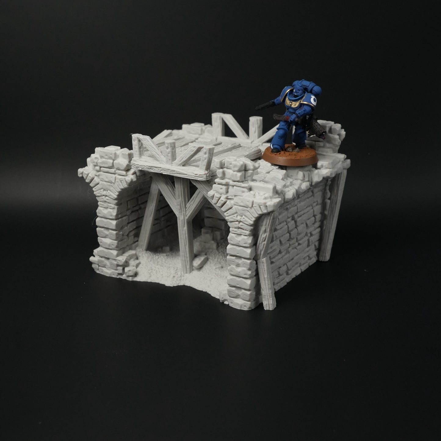 Graue zerfallene Brückenstruktur aus Stein mit Holzbalken und Miniaturfigur in Blau auf der Plattform.