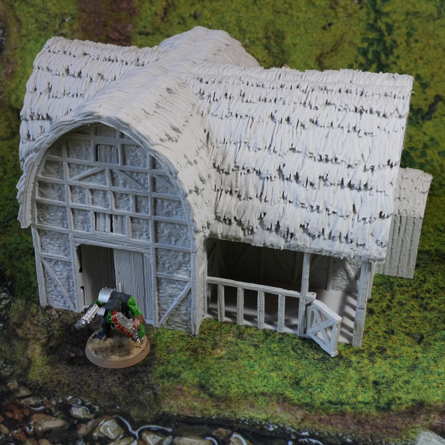 Weißer Pferdestall mit Strohdach und großen Toren auf grünem Diorama-Grund.