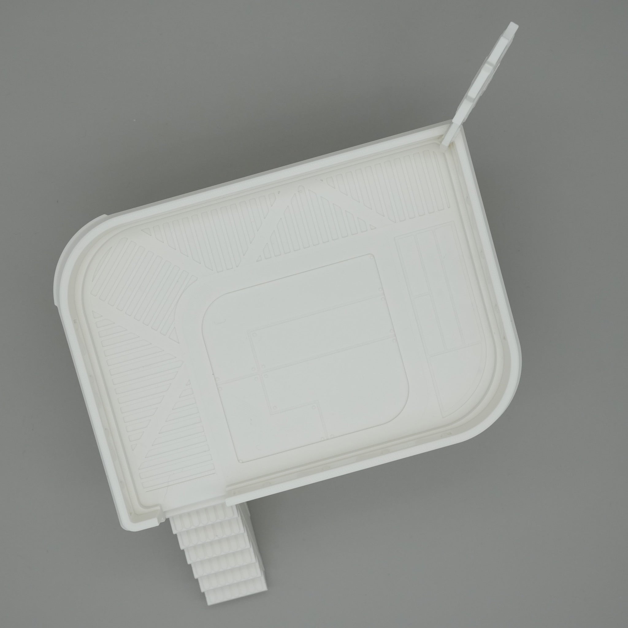 Weißes, modernes minimalistisches Modell eines Hauses mit Treppe und abgerundeten Ecken auf grauem Hintergrund.