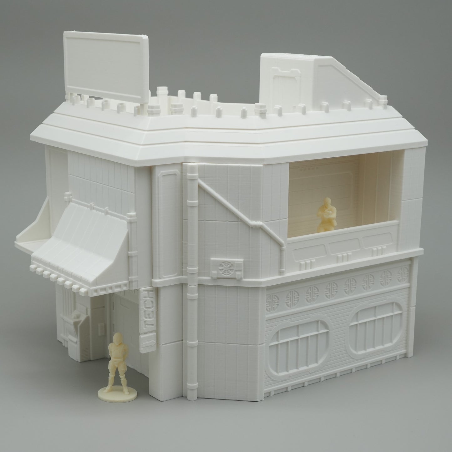 Weißes, detailreiches Modellhaus mit Flachdach, Fensterläden und zwei kleinen Figuren.