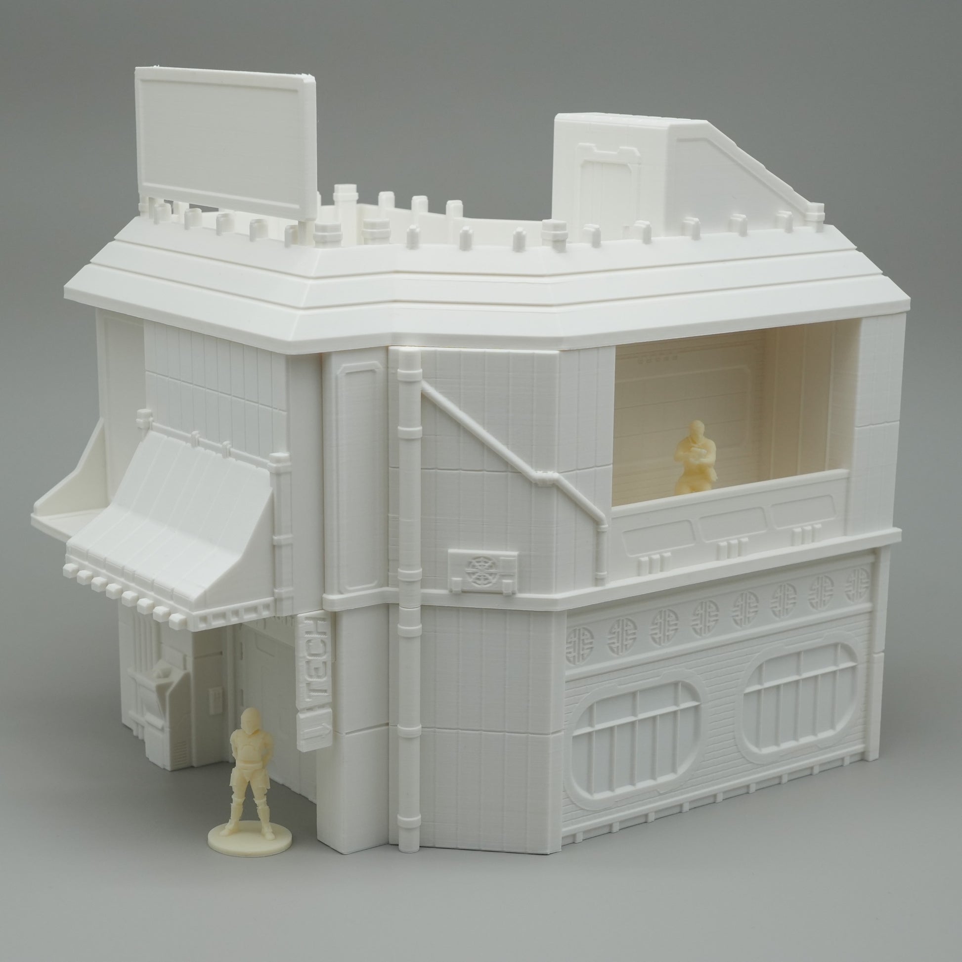 Weißes, detailreiches Modellhaus mit Flachdach, Fensterläden und zwei kleinen Figuren.
