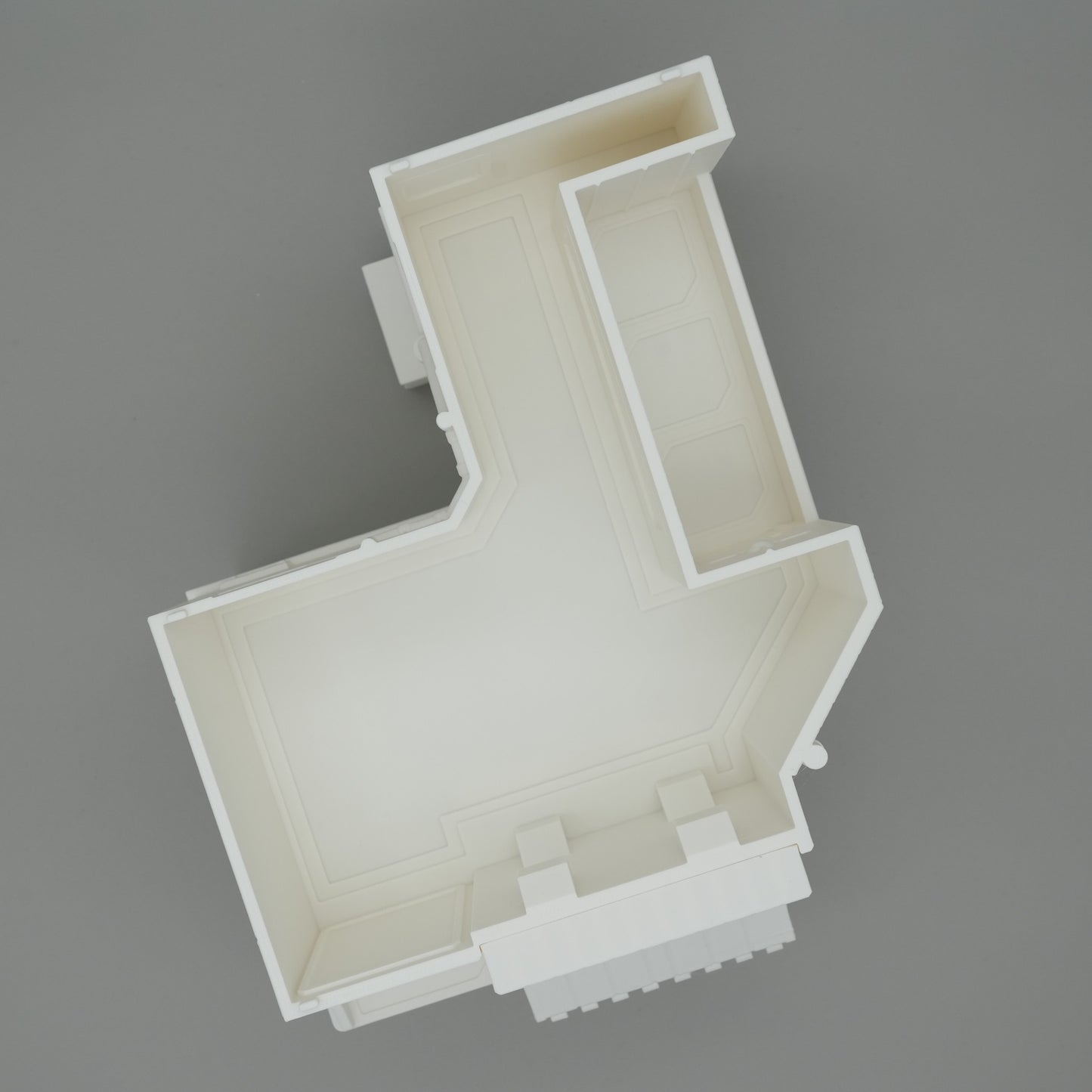 Modell eines weißen Hausgrundrisses mit klaren Wandstrukturen auf grauem Hintergrund.