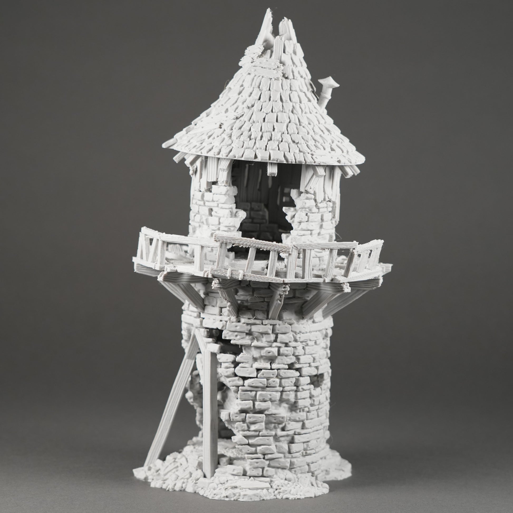 Weißer Miniatur-Turm mit zackenförmigem Dach und umlaufendem Balkon, zerklüftete Steinstruktur.