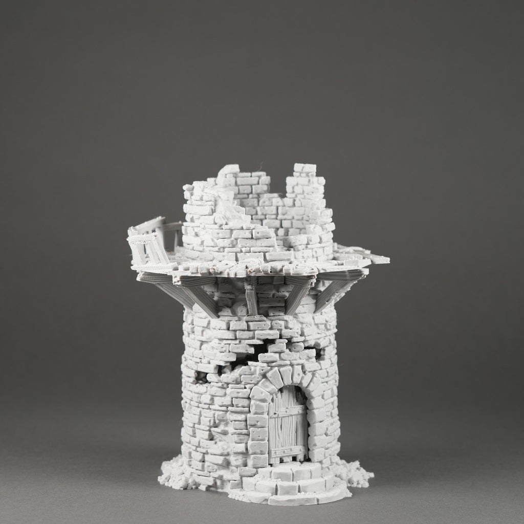 Weißer Miniatur-Turm aus zerfallenen Steinmauern mit rundem Eingang und Kranz am oberen Rand.