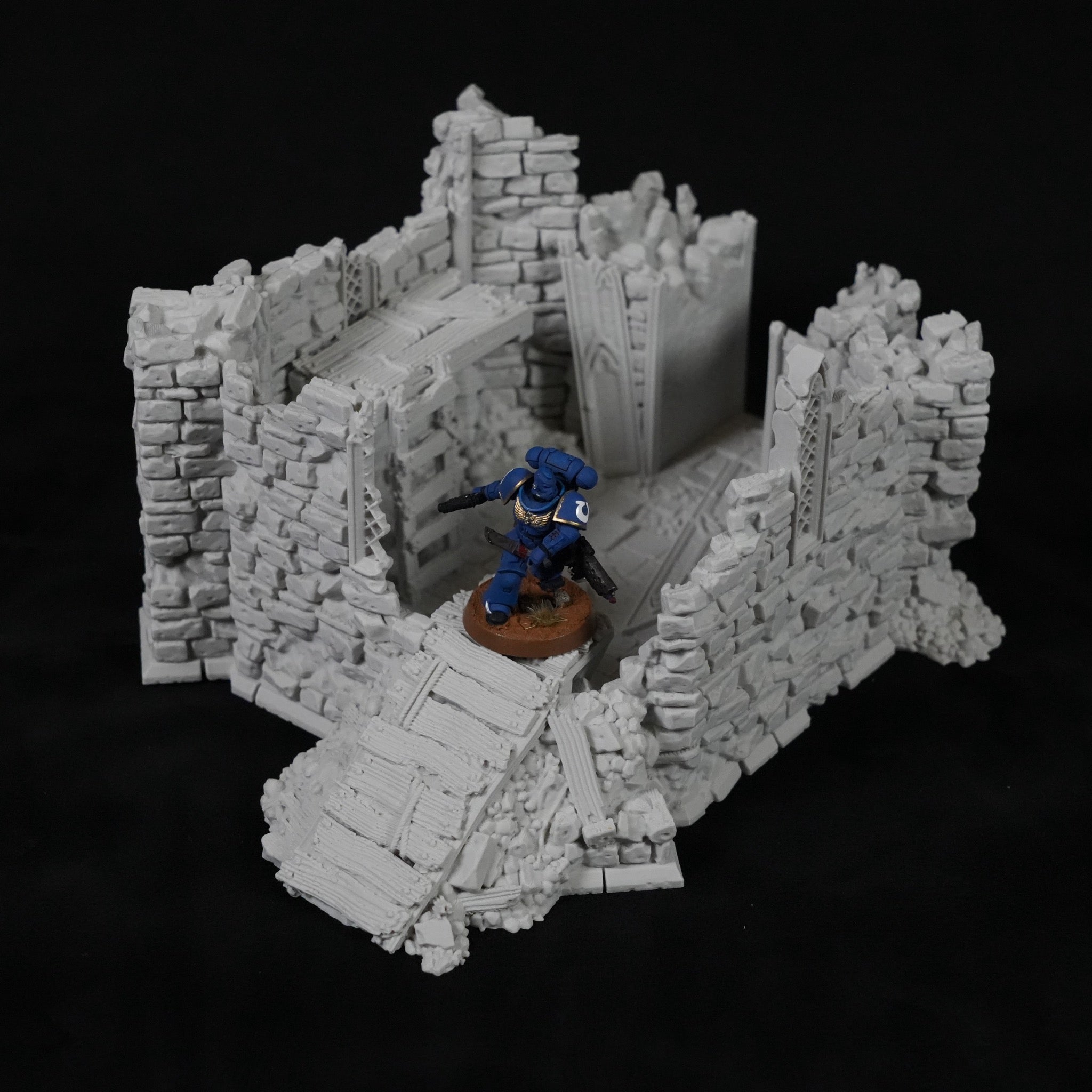 Grauer, steinerner Turm mit zerfallenen Mauern und Treppen, Miniaturfigur auf braunem Sockel.