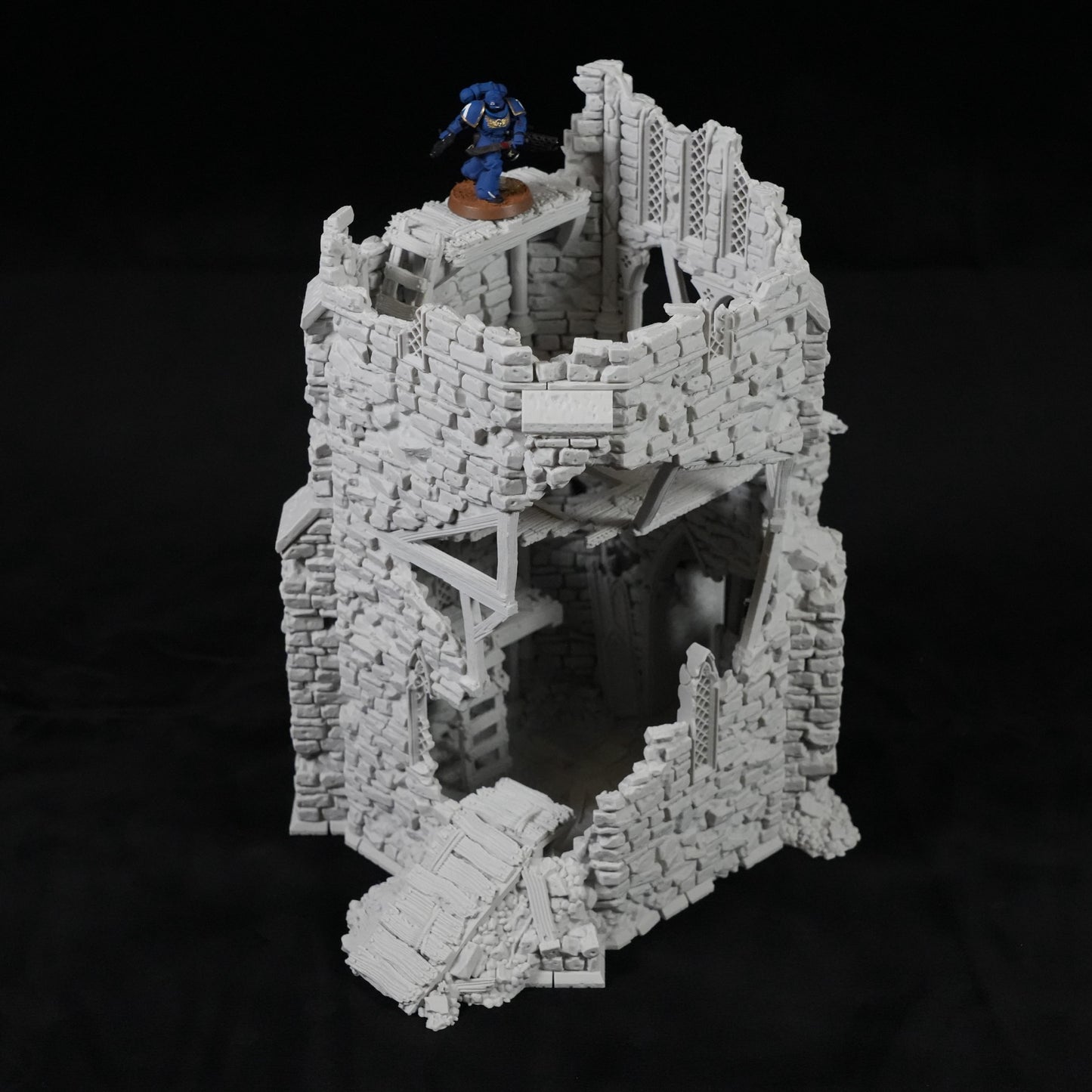 Grauer, zerfallener Turm aus Stein mit Holzbrücken und einer Miniaturfigur oben drauf.