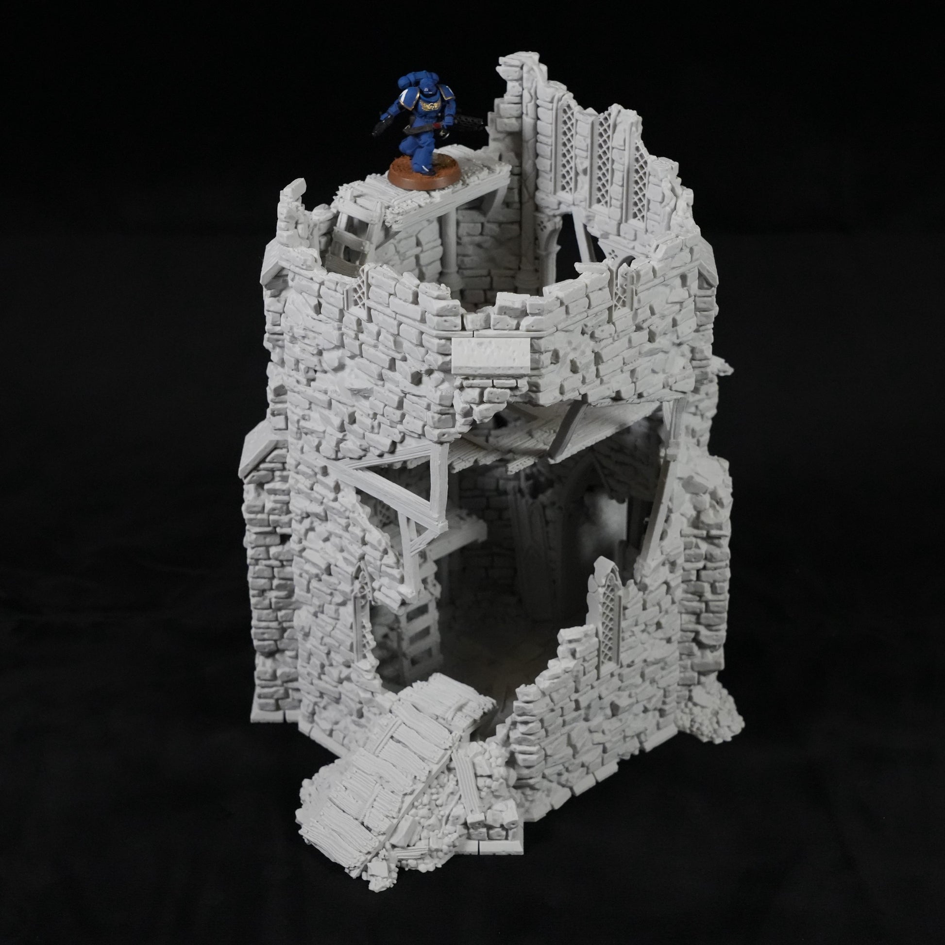 Grauer, zerfallener Turm aus Stein mit Holzbrücken und einer Miniaturfigur oben drauf.