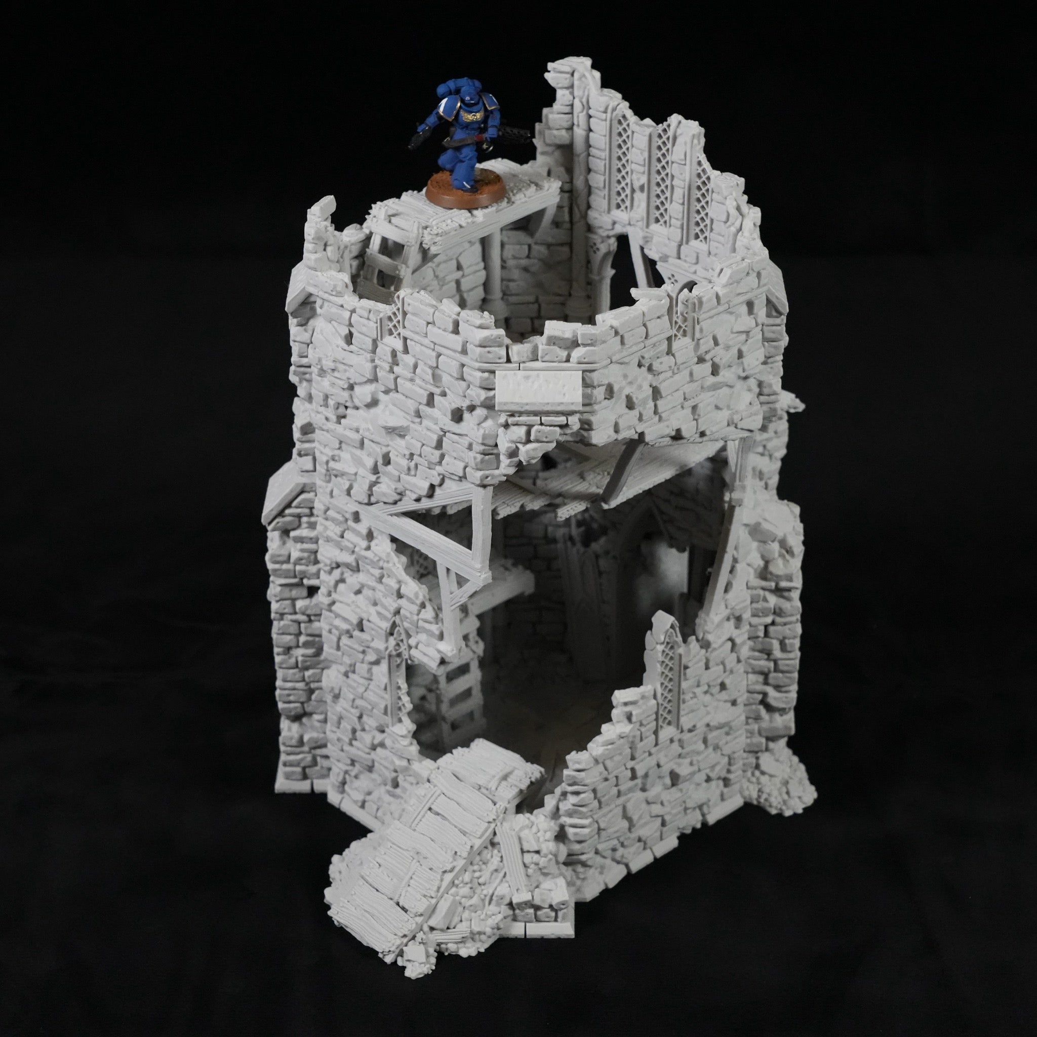 Grauer, zerfallener Turm aus Stein mit Holzbrücken und einer Miniaturfigur oben drauf.