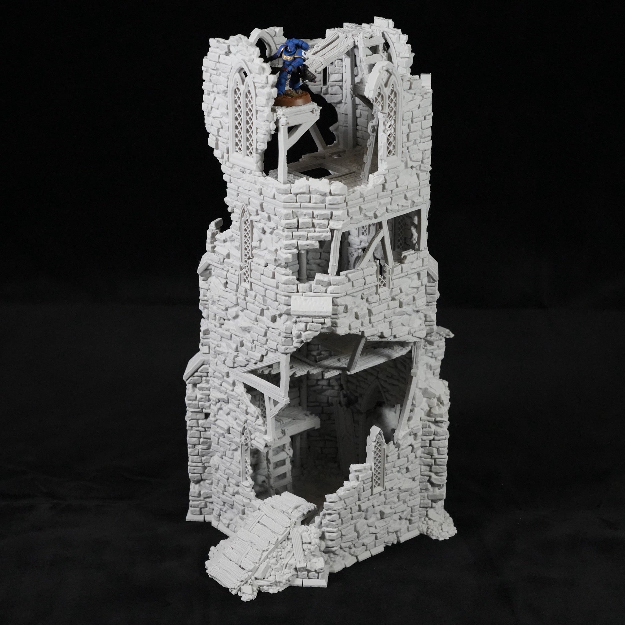 Grauer, mehrstöckiger Turm mit zerfallener Steinstruktur und innerer Wendeltreppe aus Holz.