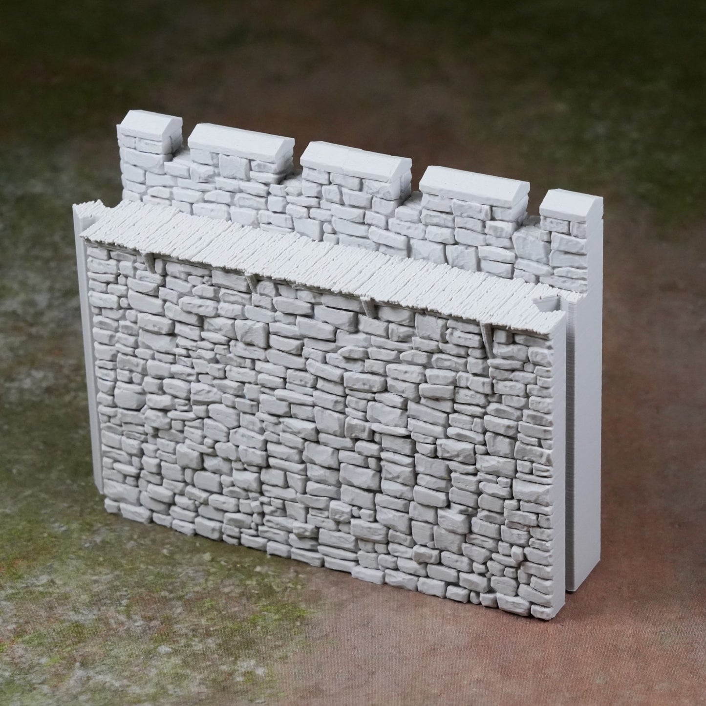 Grau bemalte, detaillierte Burgmauer mit Zinnen und Steinstruktur aus Kunststoff.