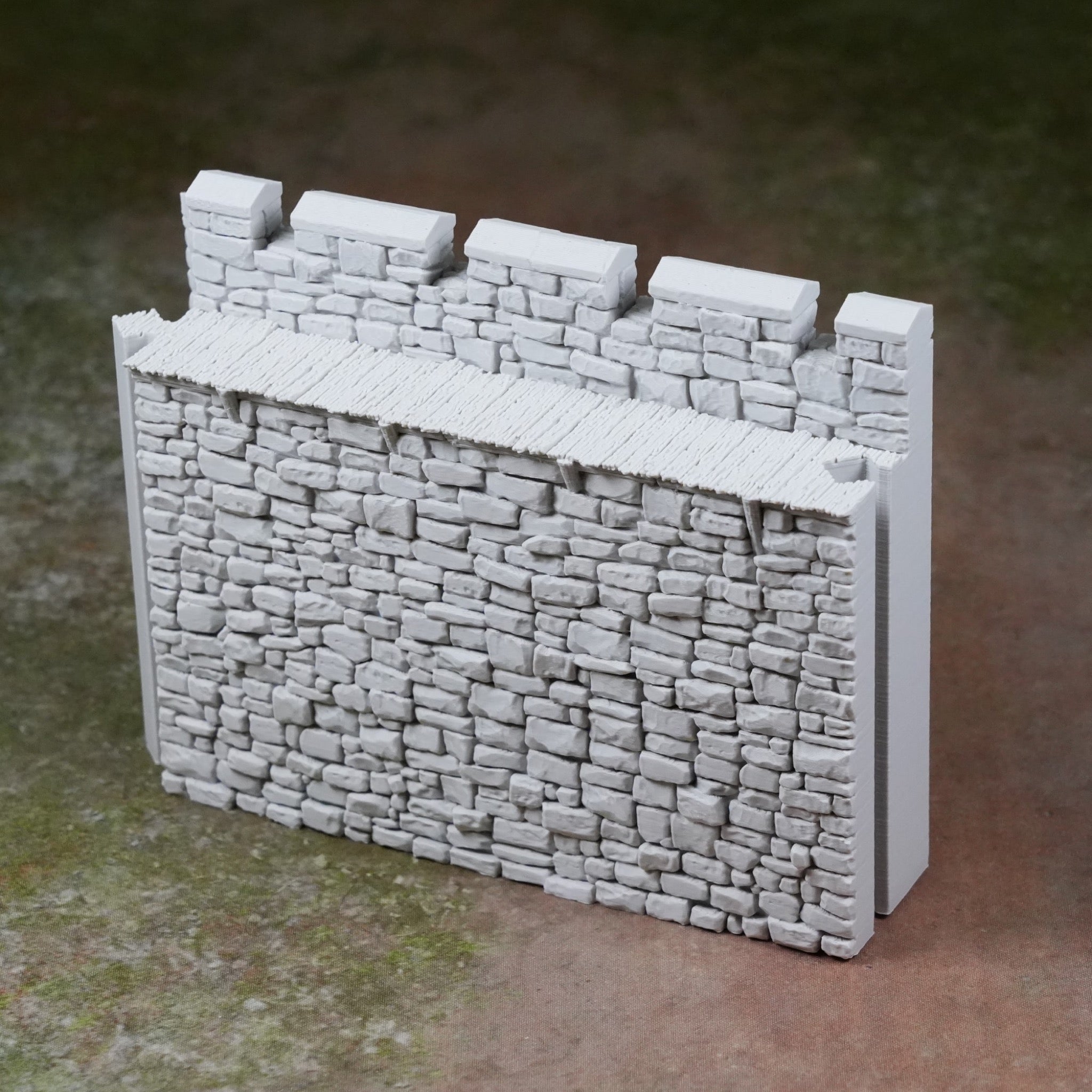 Grau bemalte, detaillierte Burgmauer mit Zinnen und Steinstruktur aus Kunststoff.