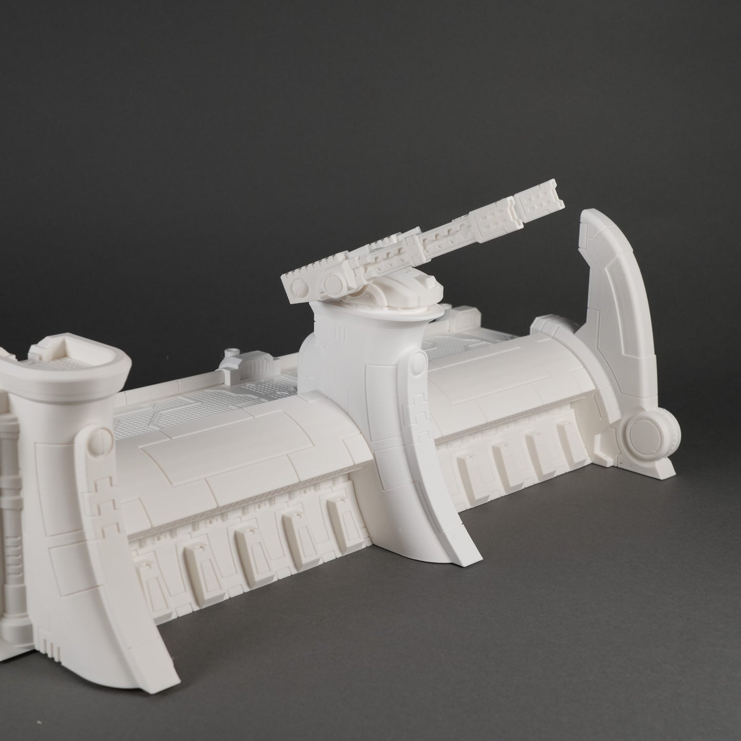 Weiße modulares Abwehrmauer-Segment mit verstärktem mittlerem Turm und seitlichen Stützpfeilern.