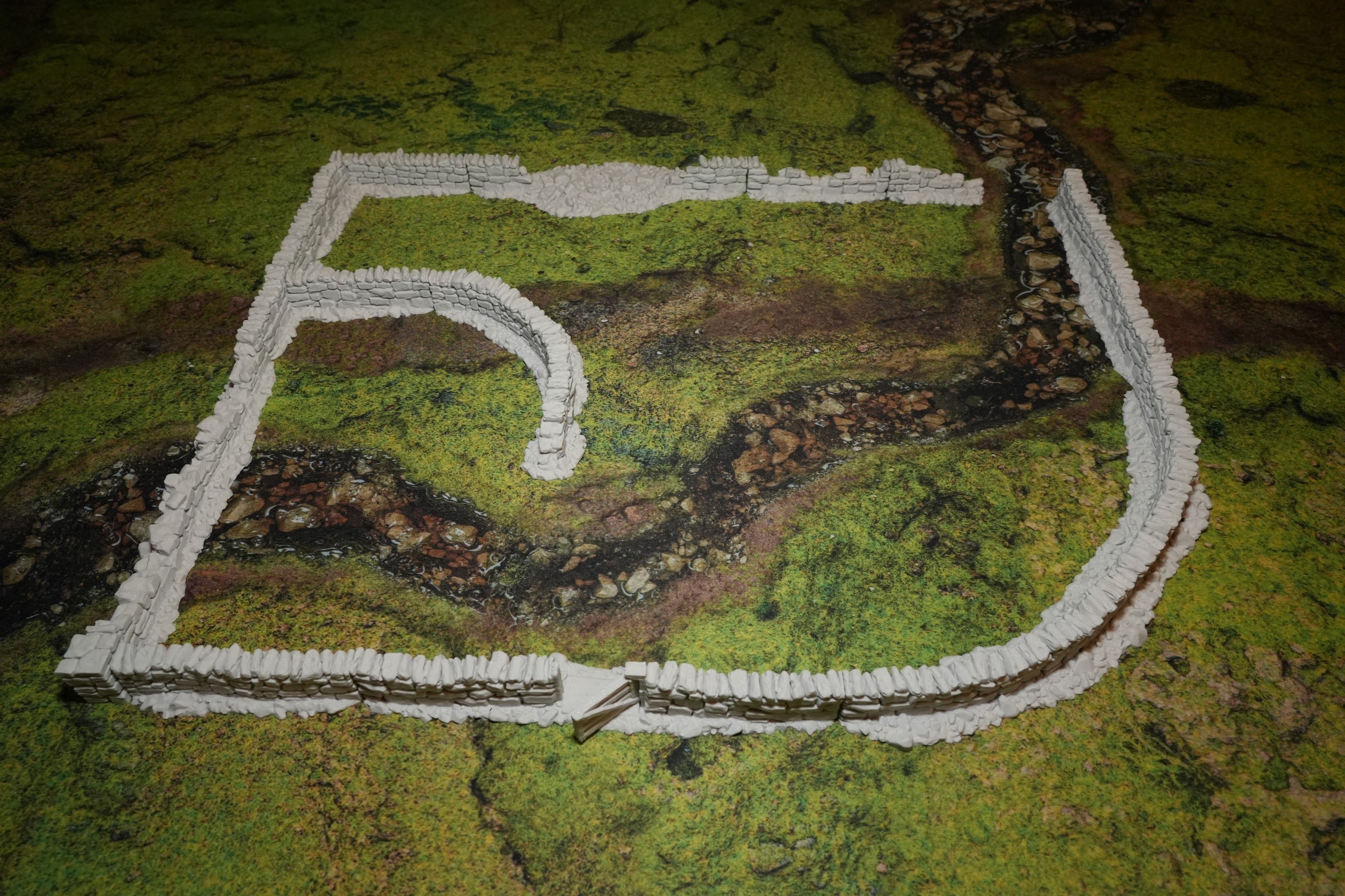 Niedrige helle Steinmauern auf moosbedecktem Untergrund mit 28mm Skalierung.