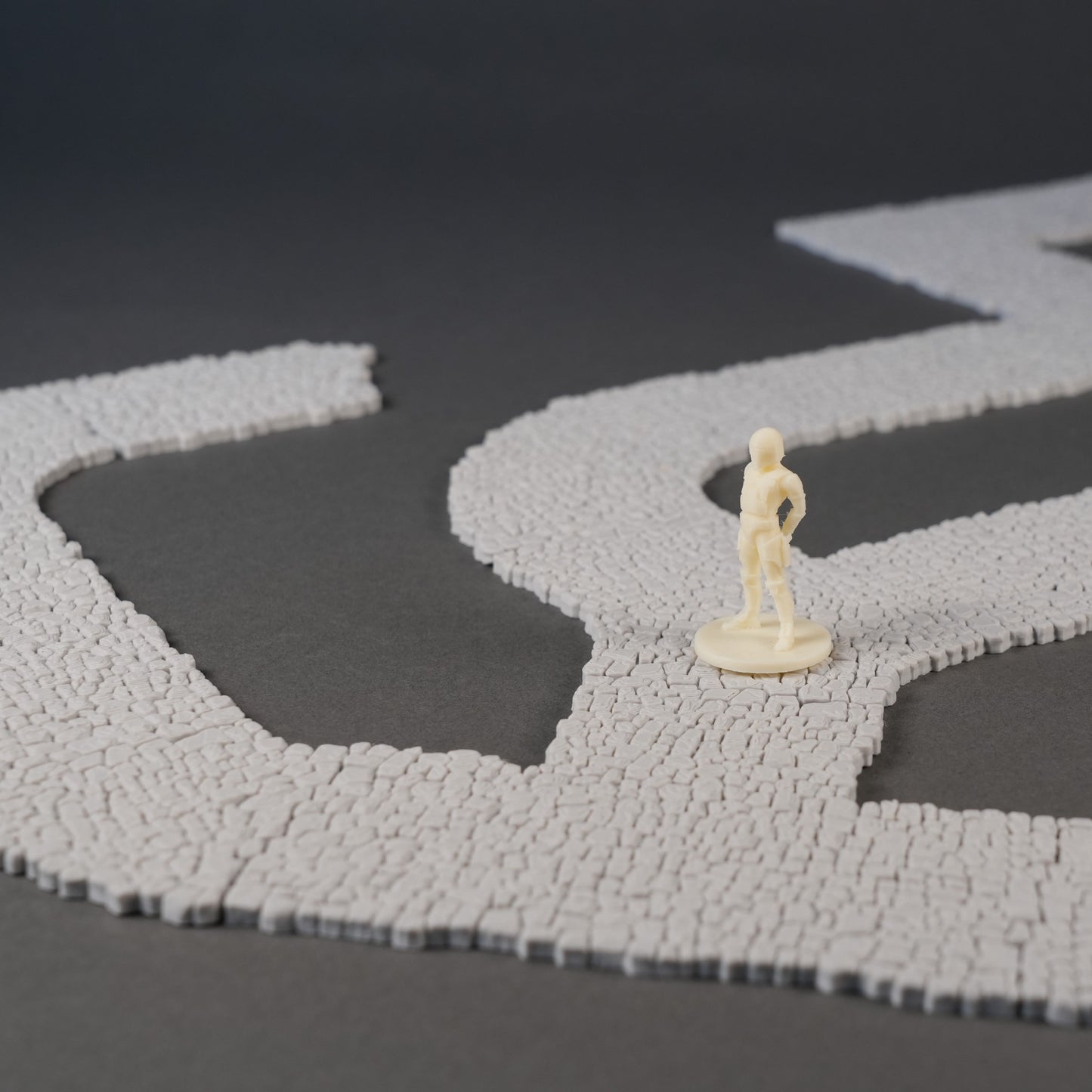 Grauer Mauer-Szenenstreuteil mit 28mm Figur auf dunklem Hintergrund.