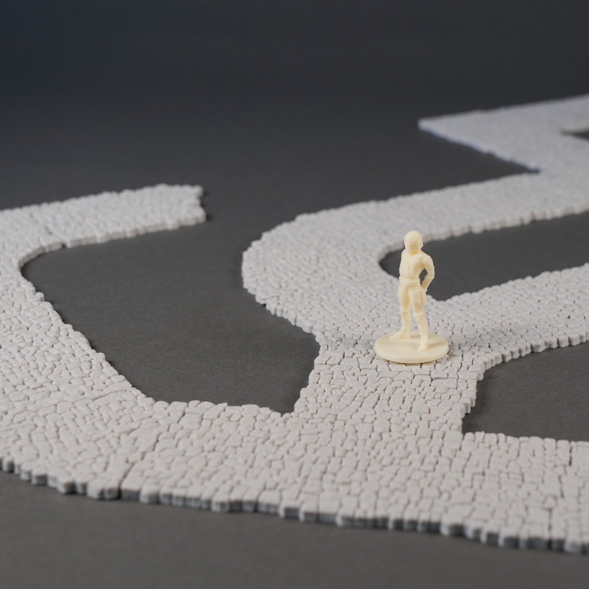 Grauer Mauer-Szenenstreuteil mit 28mm Figur auf dunklem Hintergrund.