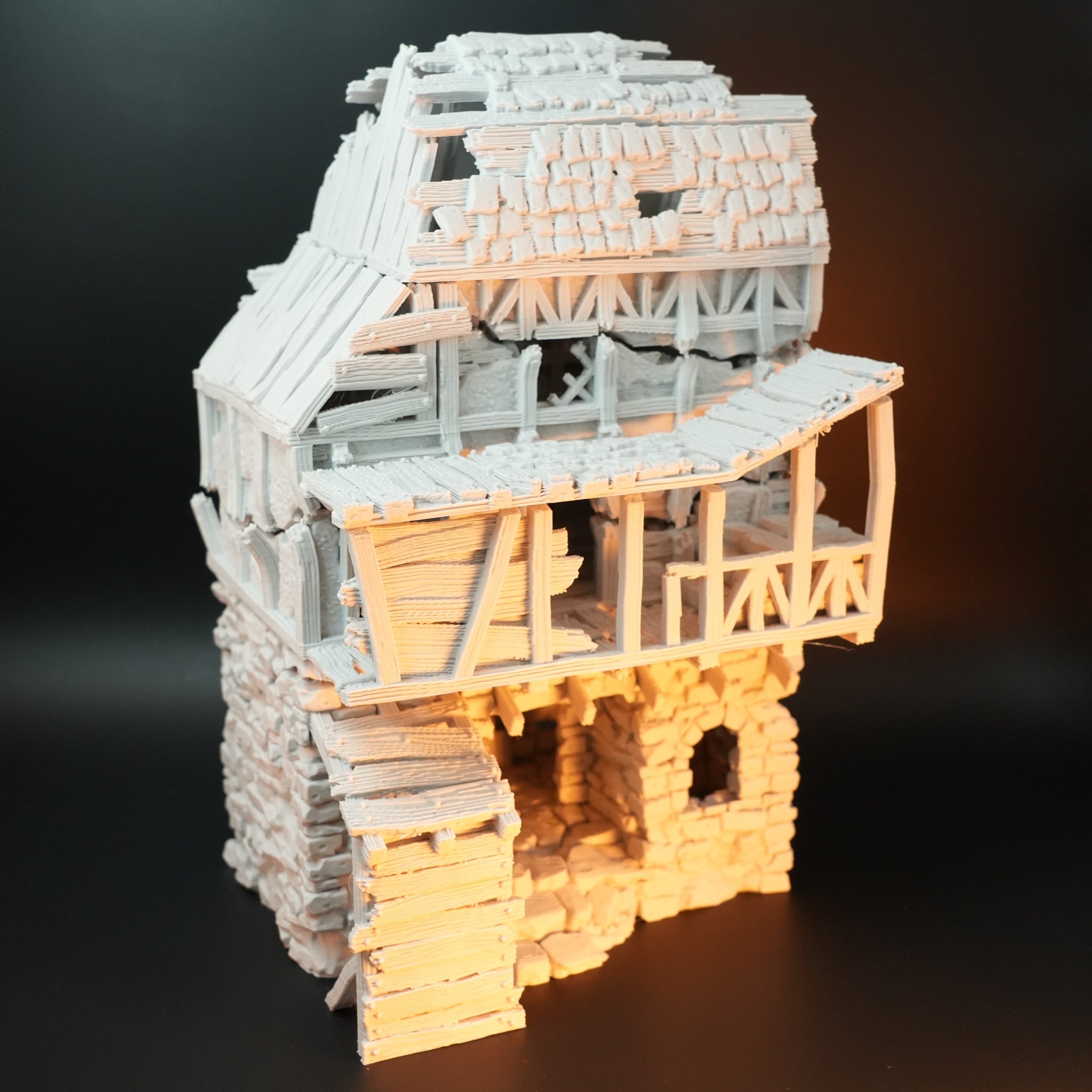 Weißes, detailreiches Modell eines zerstörten Torhauses mit Fachwerk und steinerner Basis.