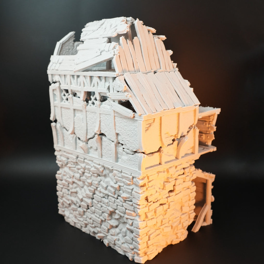 Zweistöckiges Modell eines beschädigten Torhauses mit zerfallenen Holzbalken und Steinmauerwerk.