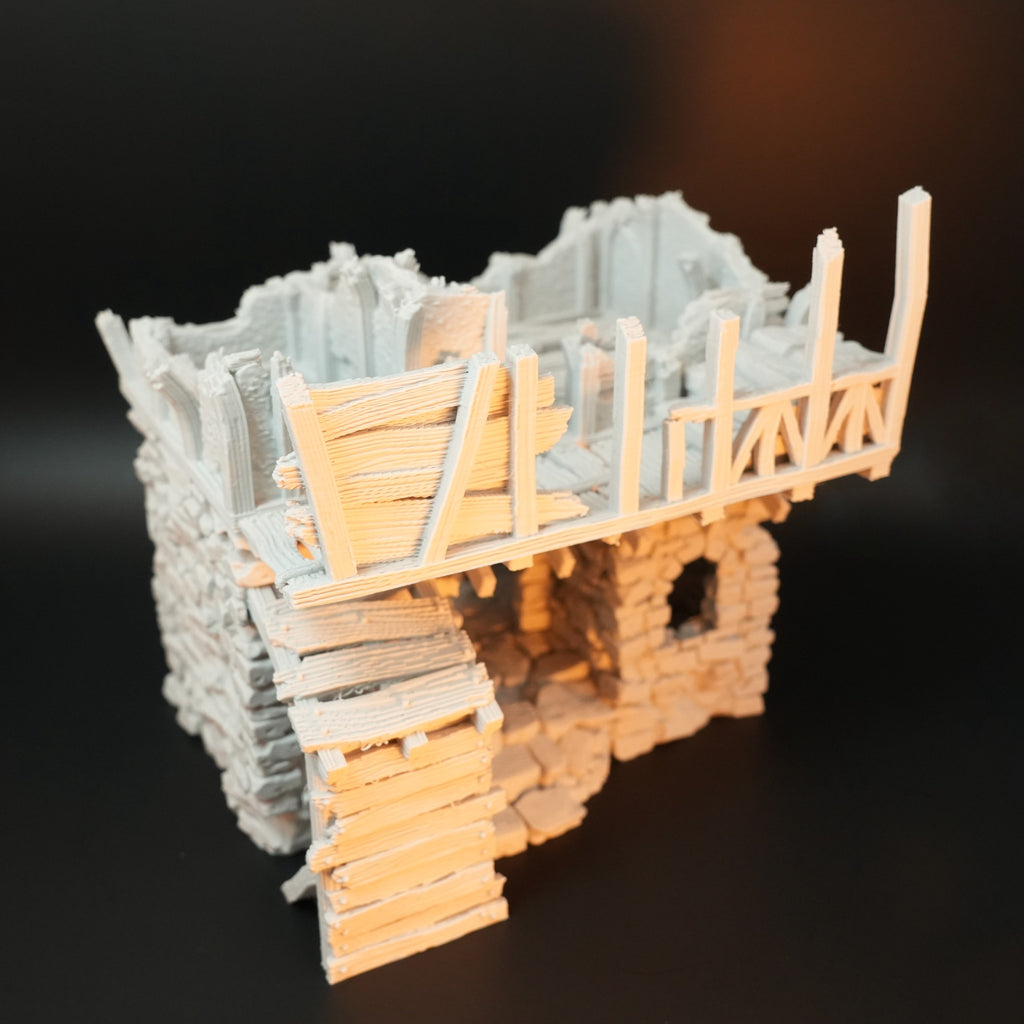 Modell eines beschädigten Torhauses aus grauem Stein mit zerstörtem Holzgeländer und Holzstufen.