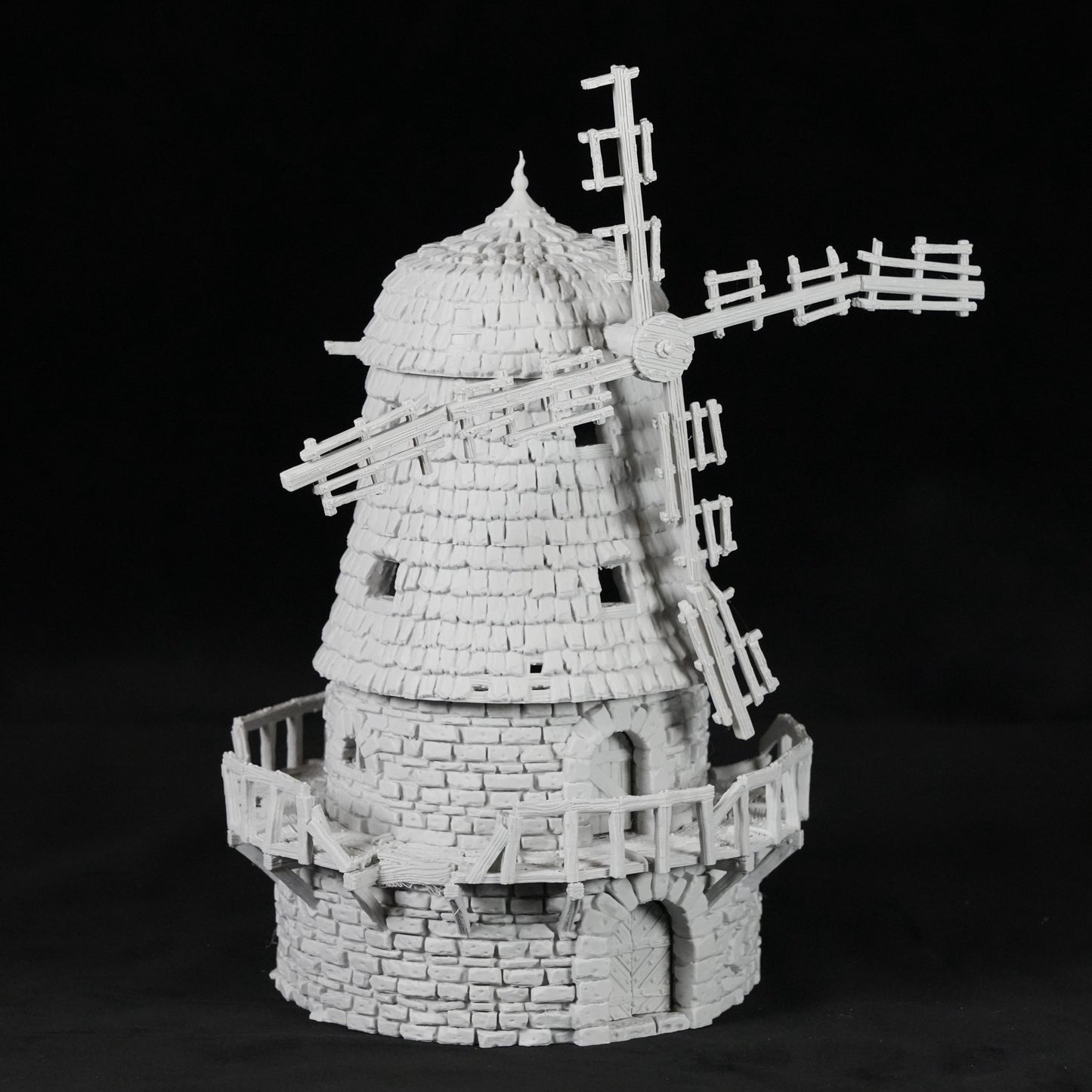 Weißes Modell einer verfallenen Windmühle aus Stein mit zerbrochenen Flügeln und Balkon.