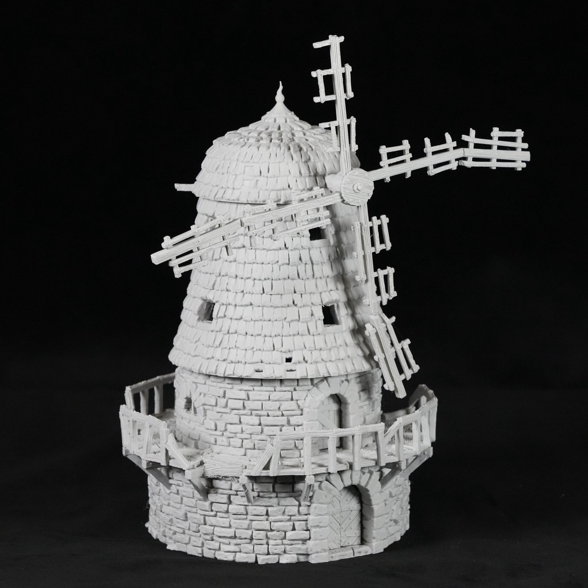 Weißes Modell einer verfallenen Windmühle aus Stein mit zerbrochenen Flügeln und Balkon.