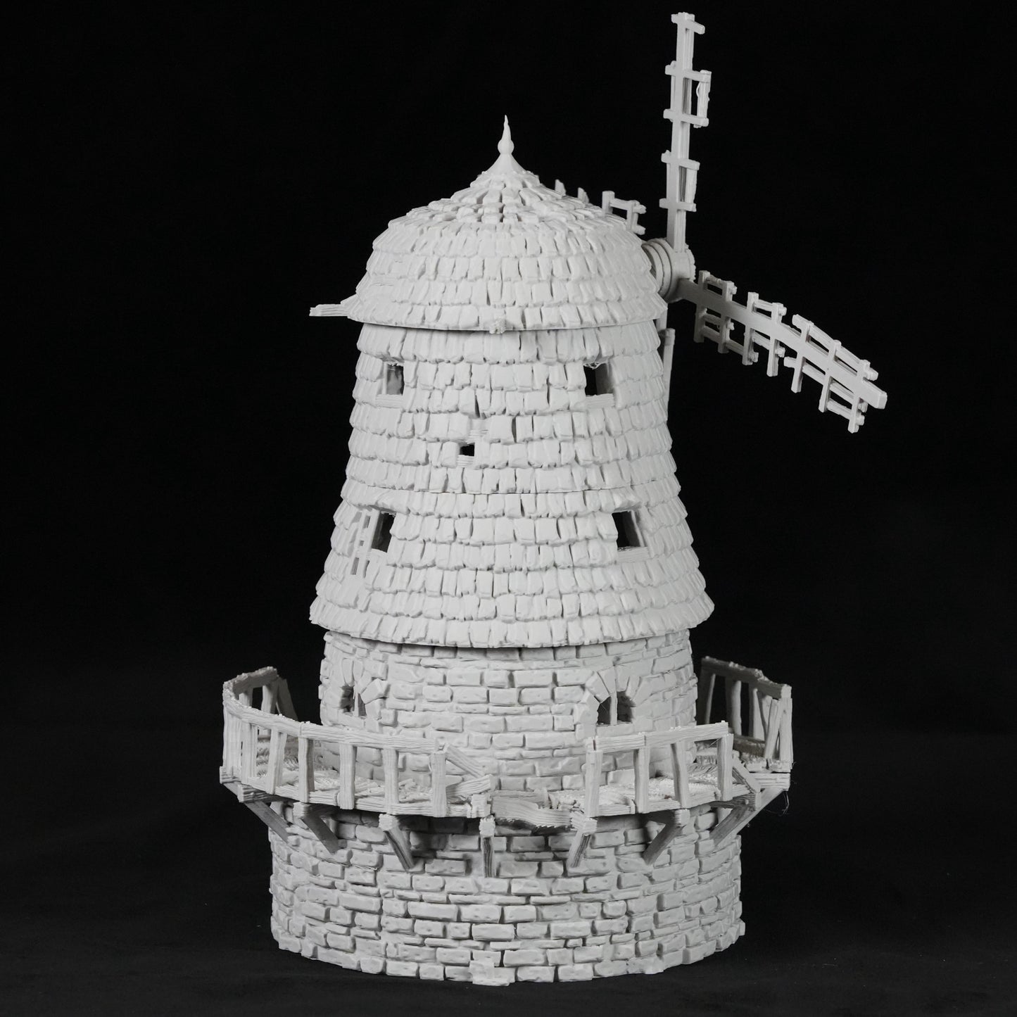 Weißes Modell einer verfallenen Windmühle mit schindelartiger Struktur und zerbrochenem Segel.