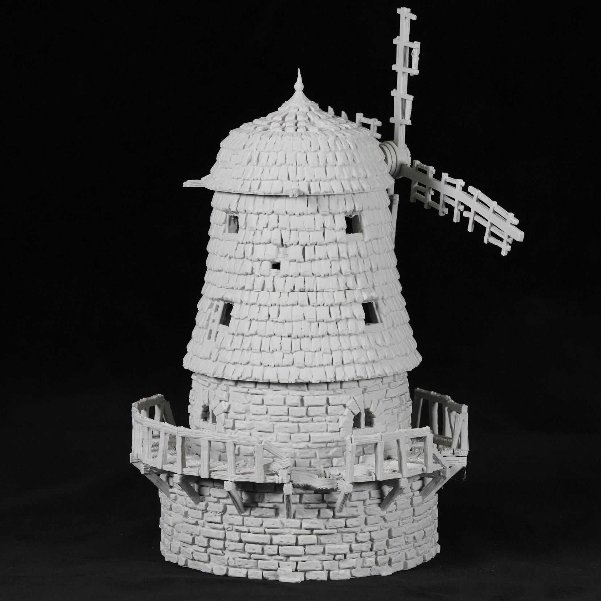 Weißes Modell einer verfallenen Windmühle mit schindelartiger Struktur und zerbrochenem Segel.
